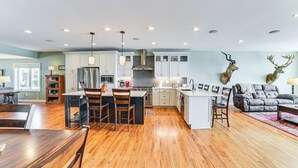 A spacious kitchen with wooden flooring, a central island, and modern appliances.