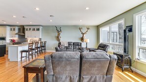 A spacious living area with a fireplace, a dining table, and a kitchen in the background.