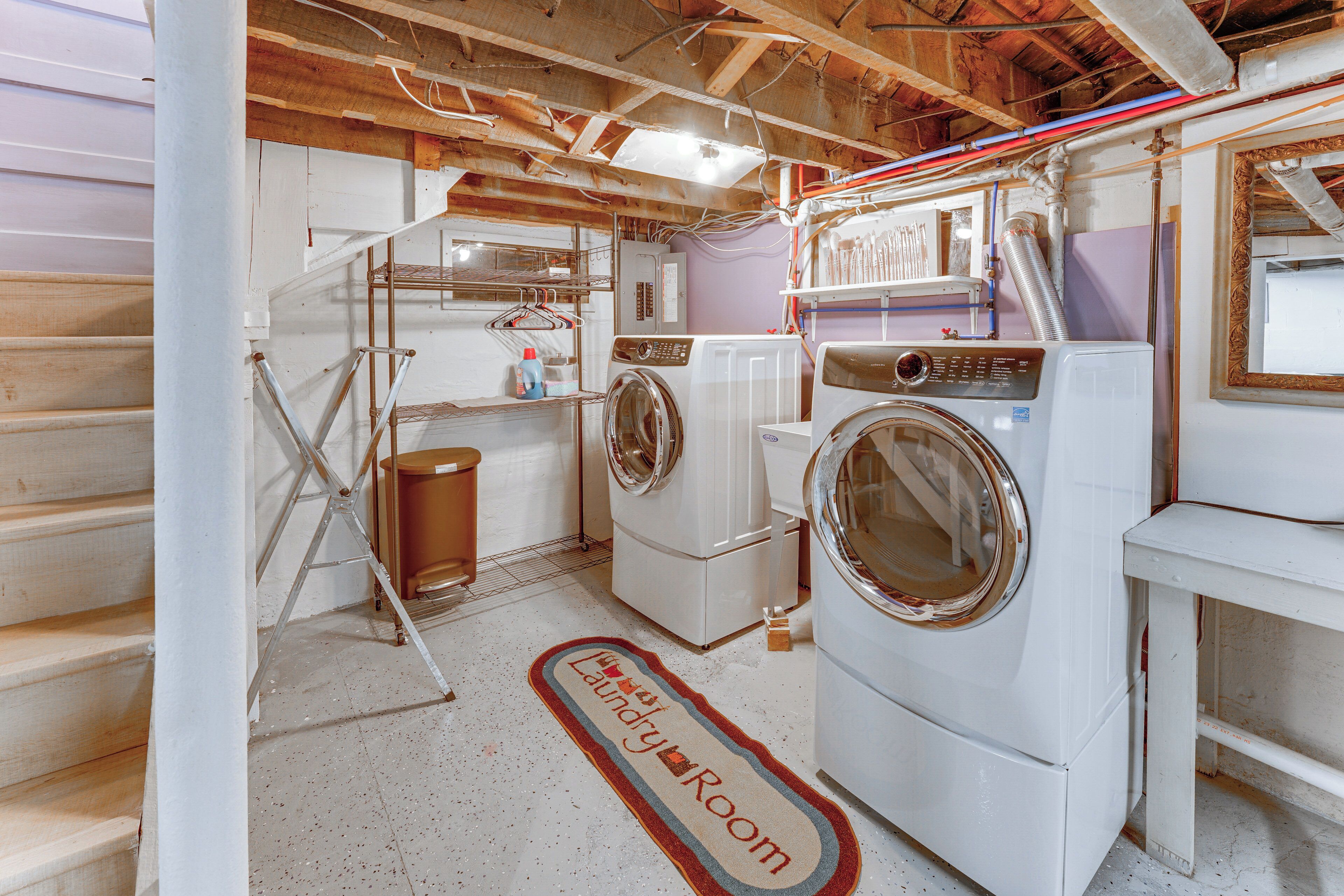 A laundry room with two washing machines, a drying rack, and a metal ladder.