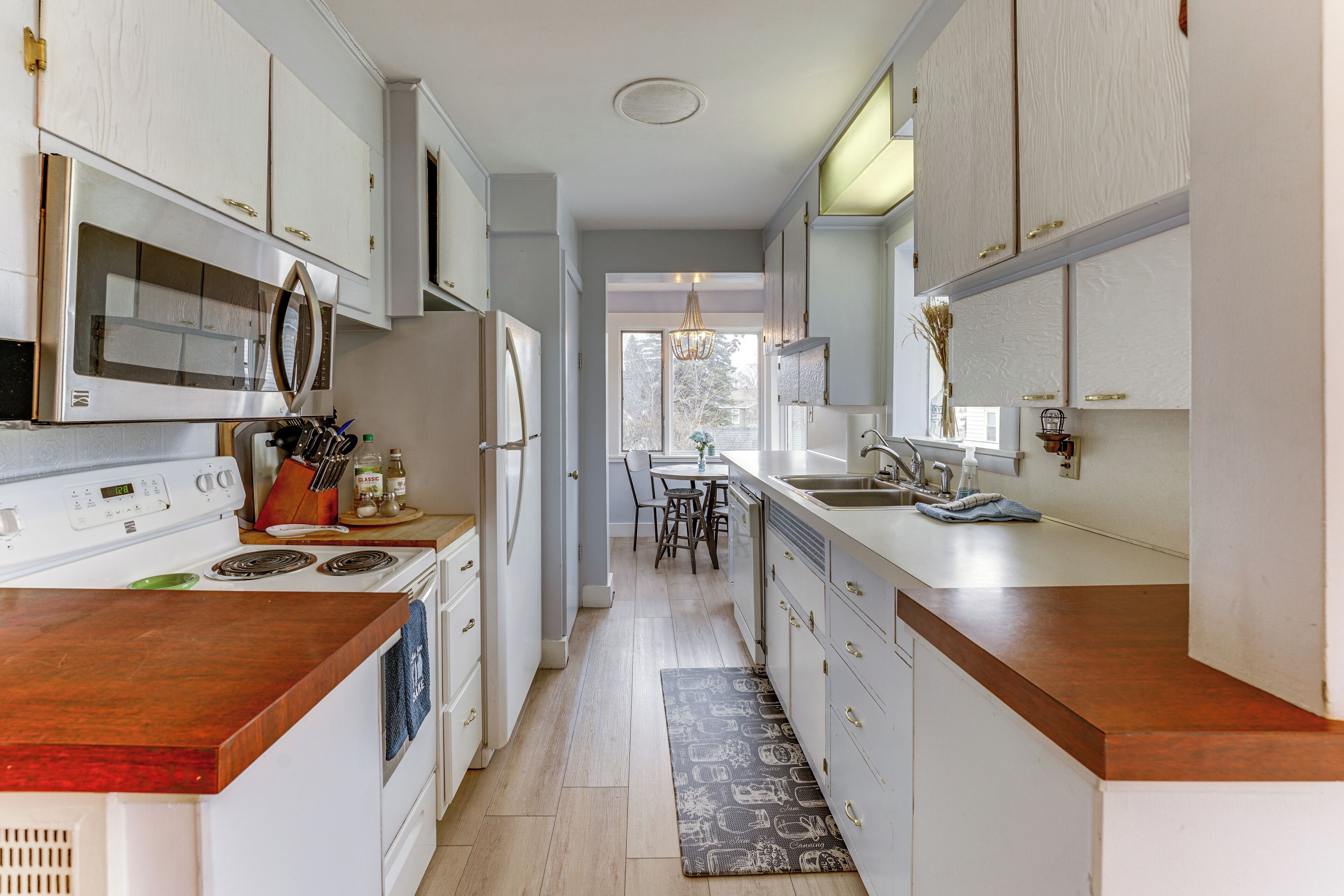 A kitchen with white cabinets, a stainless steel stove, and a wooden countertop.