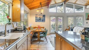 A spacious kitchen with granite countertops, wooden cabinets, and a dining area with a wooden table and chairs. - Enchanted Woodland Cabin Near Yosemite w/ Fire Pit (Groveland)