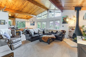 A spacious living room with leather sofas, a fireplace, and large windows.