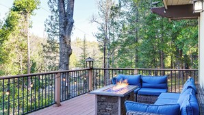 A deck with outdoor furniture and a fire feature, surrounded by trees. - Enchanted Woodland Cabin Near Yosemite w/ Fire Pit (Groveland)