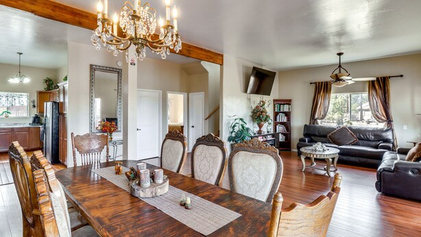 Un salon spacieux avec une table à manger en bois, des chaises décorées, un lustre et un canapé en cuir.