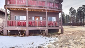 Une cabane en bois à deux étages, dotée d’un balcon, d’une échelle en bois et dont le sol est recouvert de neige.