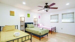 A bedroom with two beds, a ceiling fan, and wall-mounted light fixtures. - Pool & Game Room: Spacious Brandon Home (Brandon)