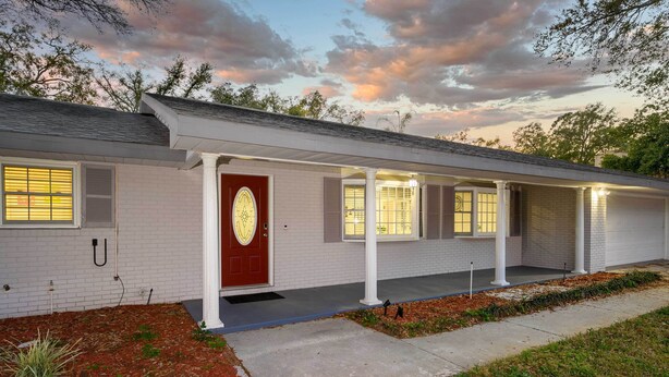 A single-story house with a red door, white columns, and a covered porch. - Pool & Game Room: Spacious Brandon Home (Brandon)