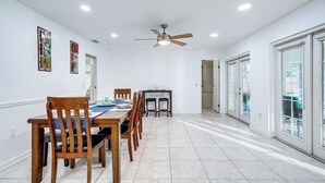 A dining area with a wooden table and chairs, a ceiling fan, and a view through glass doors. - Pool & Game Room: Spacious Brandon Home (Brandon)