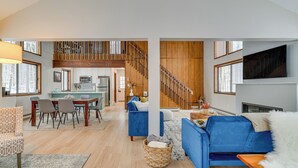 Ein geräumiger Wohnbereich mit Esstisch, blauen Sofas und einer Treppe, die in eine obere Etage führt.