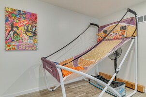 Una habitación con un aro de baloncesto, un cartel llamativo en la pared y un ventilador cerca de la puerta.