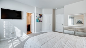 A bedroom with a large bed, a flat-screen TV mounted on the wall, a dresser, and a door leading to another room. - Union City Townhome: 17 Mi to Downtown Atlanta! (Union City)