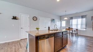 A kitchen with a dishwasher, a sink, and a dining area with chairs. - Union City Townhome: 17 Mi to Downtown Atlanta! (Union City)