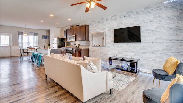 A spacious living area with a sofa, a coffee table, and a TV mounted on the wall. - Union City Townhome: 17 Mi to Downtown Atlanta! (Union City)