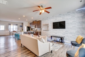 A spacious living area with a sofa, a coffee table, and a TV mounted on the wall.