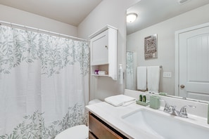 A bathroom with a shower curtain, a sink, a mirror, and a towel rack.