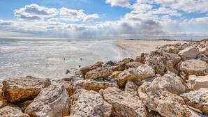 Una spiaggia rocciosa con cielo sereno e mare calmo.