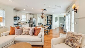 A spacious living room with a sofa and ottoman, a dining area with a chandelier, and a kitchen in the background. - Tranquil Arrington Cottage ~ 7 Mi to Franklin! (Arrington)