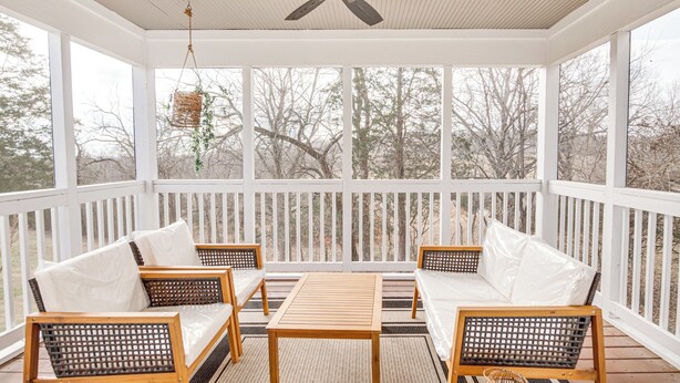 A covered porch with white railings, wicker furniture, and a ceiling fan. - Tranquil Arrington Cottage ~ 7 Mi to Franklin! (Arrington)