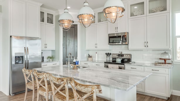A modern kitchen with white cabinetry, a central island, and three pendant lights. - 'footprints in the Sand' - Luxe Freeport Home! (Freeport)