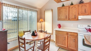 Una cucina con mobili in legno, un piano cottura bianco e un'area pranzo con tavolo e sedie.