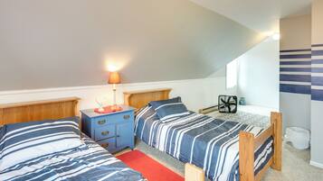 A bedroom with two beds, a nightstand, a lamp, and a fan.