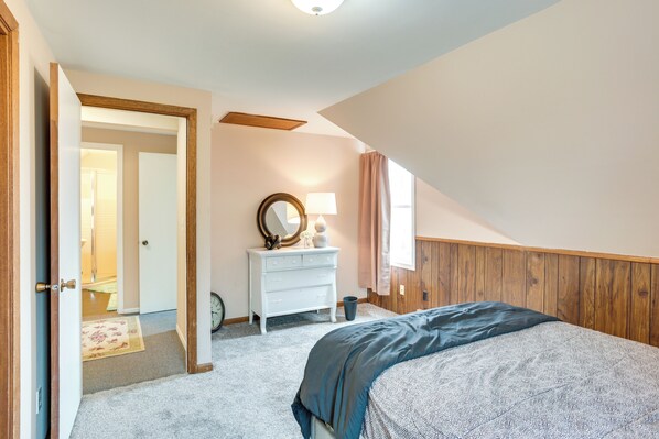 A bedroom with a bed, a dresser, a mirror, and a door leading to another room. - Countryside Retreat on Cokato Lake w/ Indoor Sauna (Cokato)