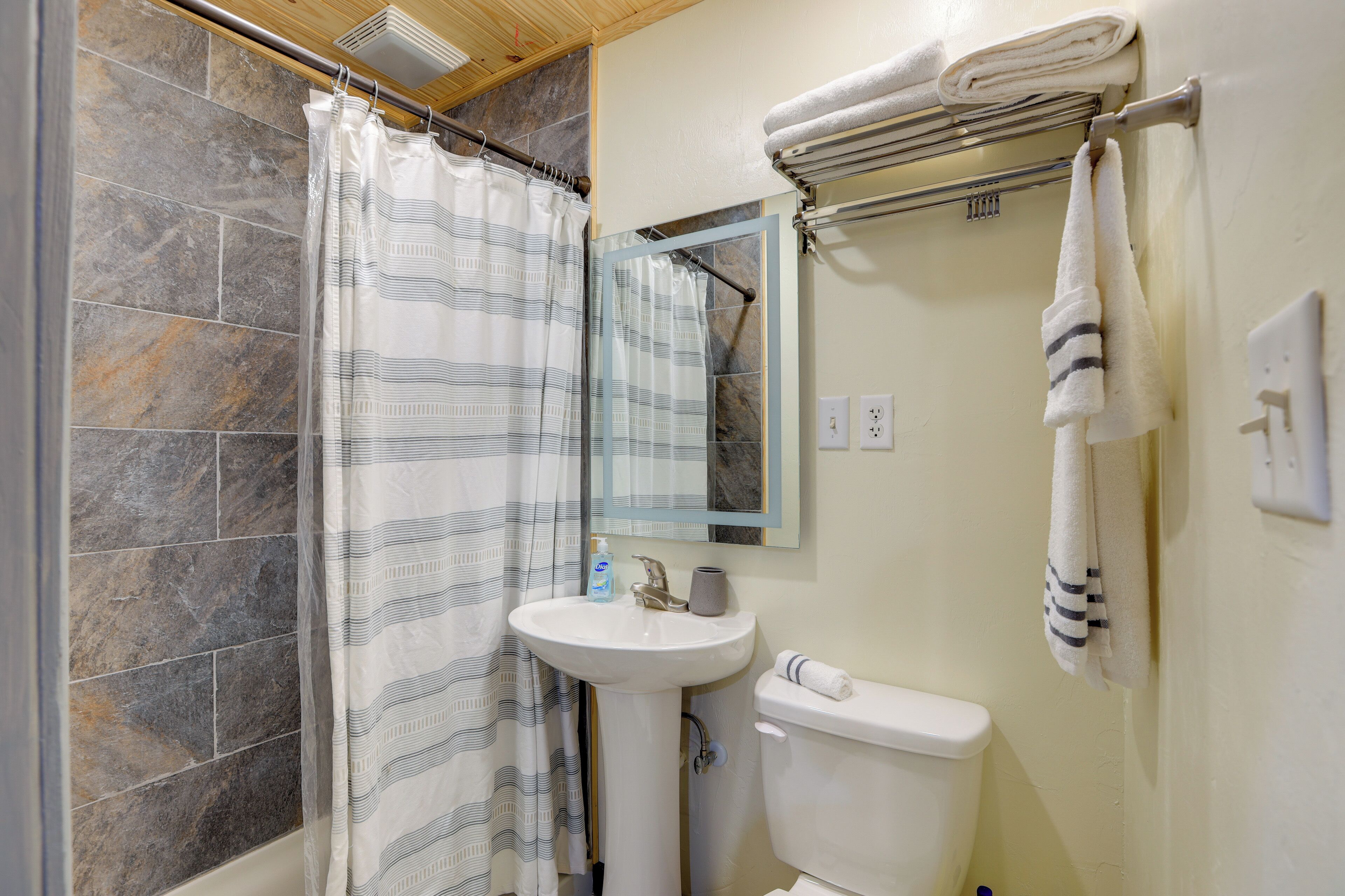 Un baño con ducha, lavabo, inodoro y toallero.