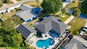 Vista aérea de una zona residencial con piscina, varias casas y un patio cercado.