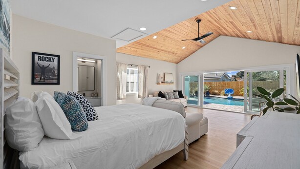 Un dormitorio espacioso con una cama grande, un sofá y vistas a una piscina.