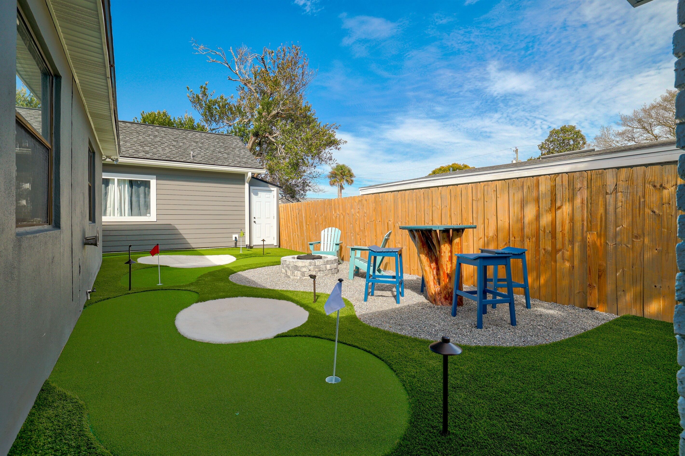 A backyard with artificial grass, a wooden fence, and outdoor furniture.