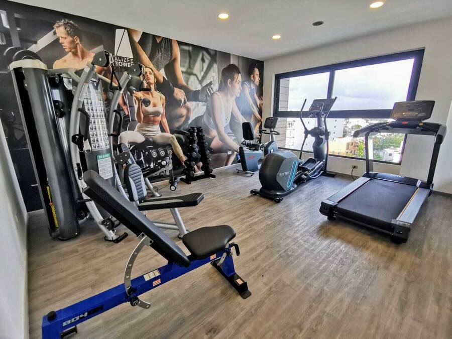 Una palestra con tapis roulant, panca per pesi e diverse macchine per esercizi.