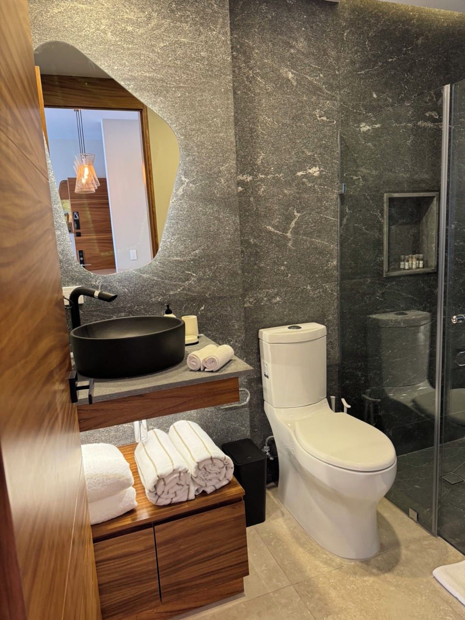 Un baño moderno con lavamanos de mármol, inodoro y cabina de ducha de vidrio.