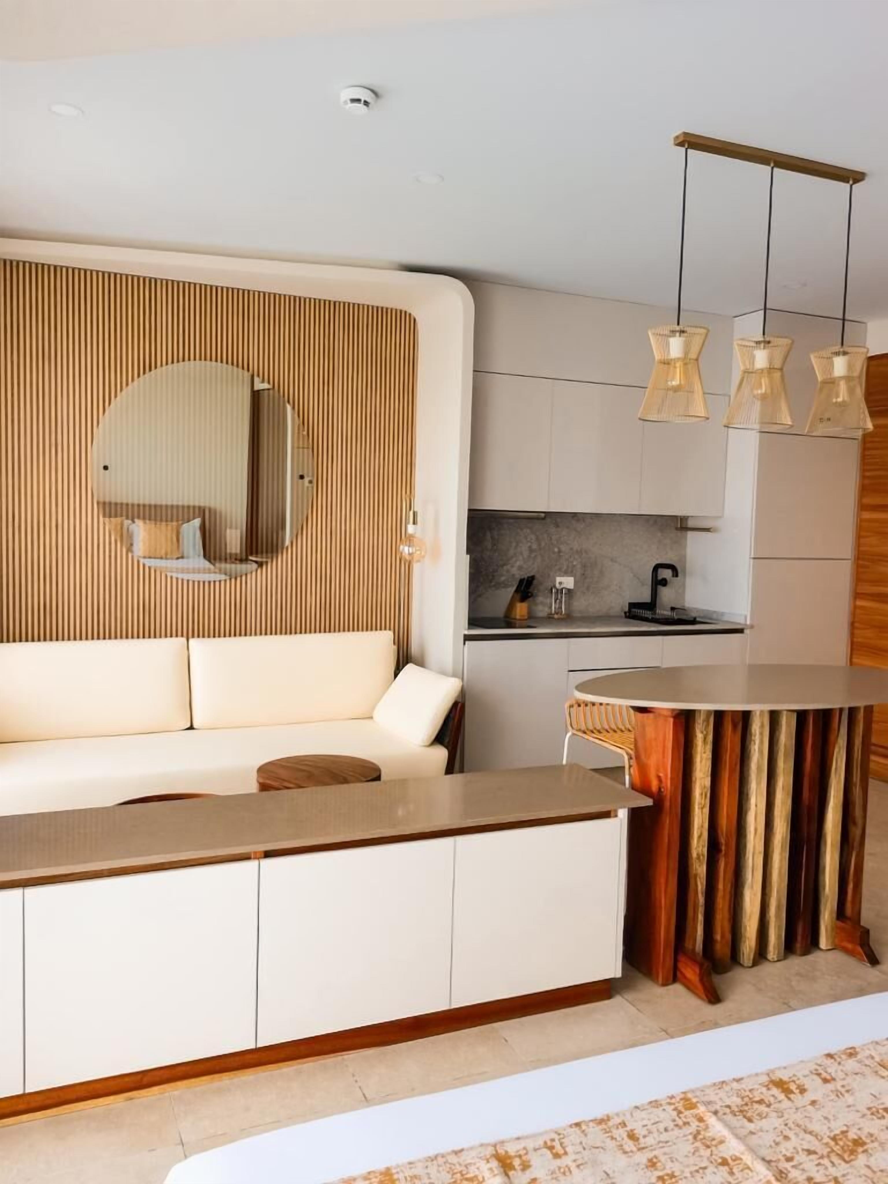 A modern living room with a sofa, a round wooden table, and a kitchen area in the background.