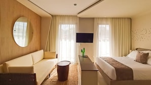 A modern hotel room with a sofa, a bed, a TV, and a small table. - Alizee Tower (Playa del Carmen)