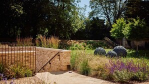 A landscaped garden with a brick wall, a metal fence, and various plants. - Rhodes House (Oxford)