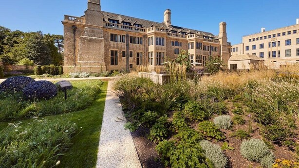 A large, historic building with a symmetrical facade, multiple chimneys, and a well-maintained garden with a gravel path. - Rhodes House (Oxford)