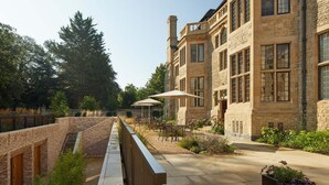 A courtyard with outdoor seating, stone buildings, and a brick wall. - Rhodes House (Oxford)