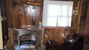A rustic interior with a stone fireplace, wooden ceiling, and a leather armchair. - Residencial El Cielo a Wonderful Place in the mountain range at Los Naranjos ESV (Los Naranjos)