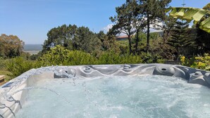 A hot tub surrounded by lush greenery and trees, with a clear view of the landscape in the background. - Spacious 4 bed house with hot tub, games room & terraces, near Alcobaca & Nazare (Vestiaria)