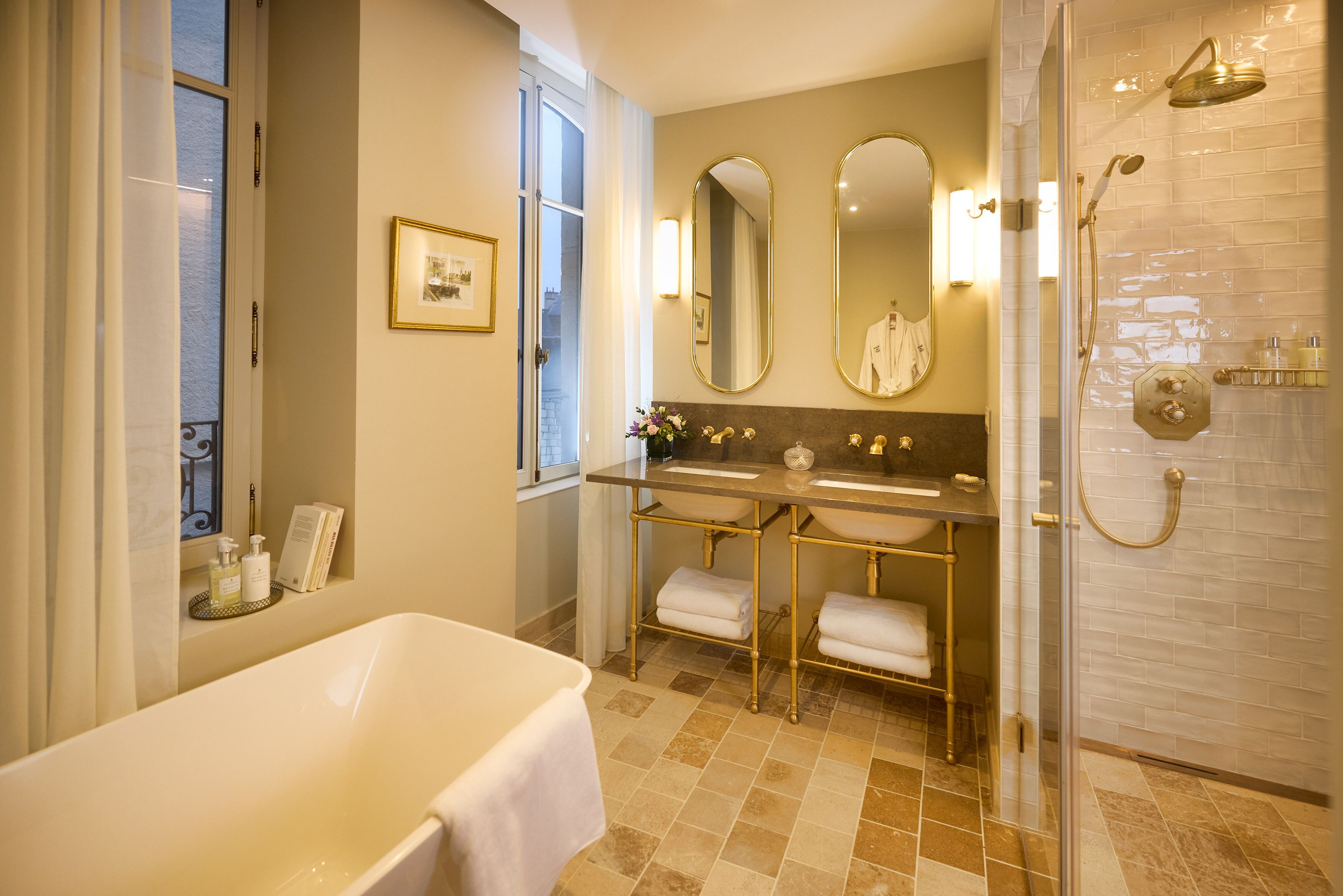 A modern bathroom with a bathtub, a double sink vanity, and a glass-enclosed shower area.