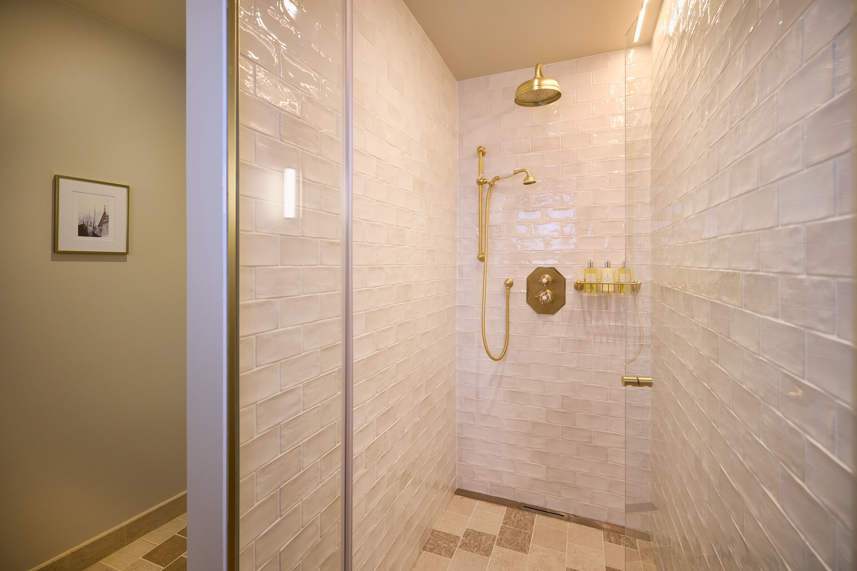 A walk-in shower with white tiled walls and a glass door.
