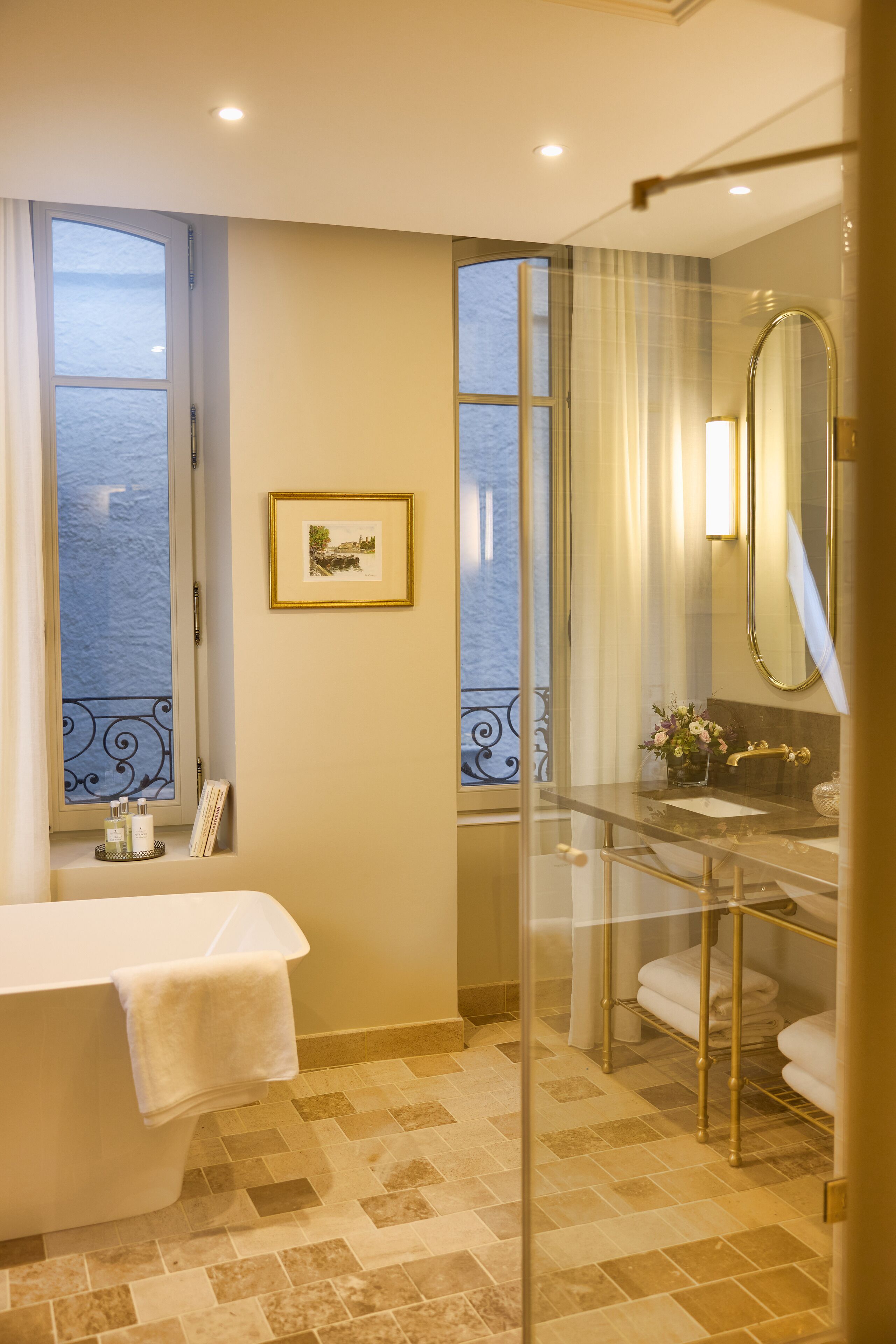 A bathroom with a bathtub, a glass-enclosed shower, a vanity with a mirror, and a framed picture on the wall.