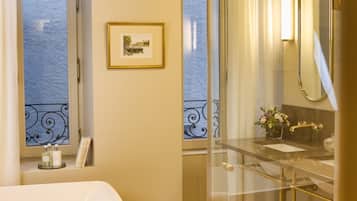 A bathroom with a bathtub, a glass-enclosed shower, a vanity with a mirror, and a framed picture on the wall.