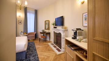 A hotel room with a bed, a sofa, a fireplace, a television, and a desk with a chair.