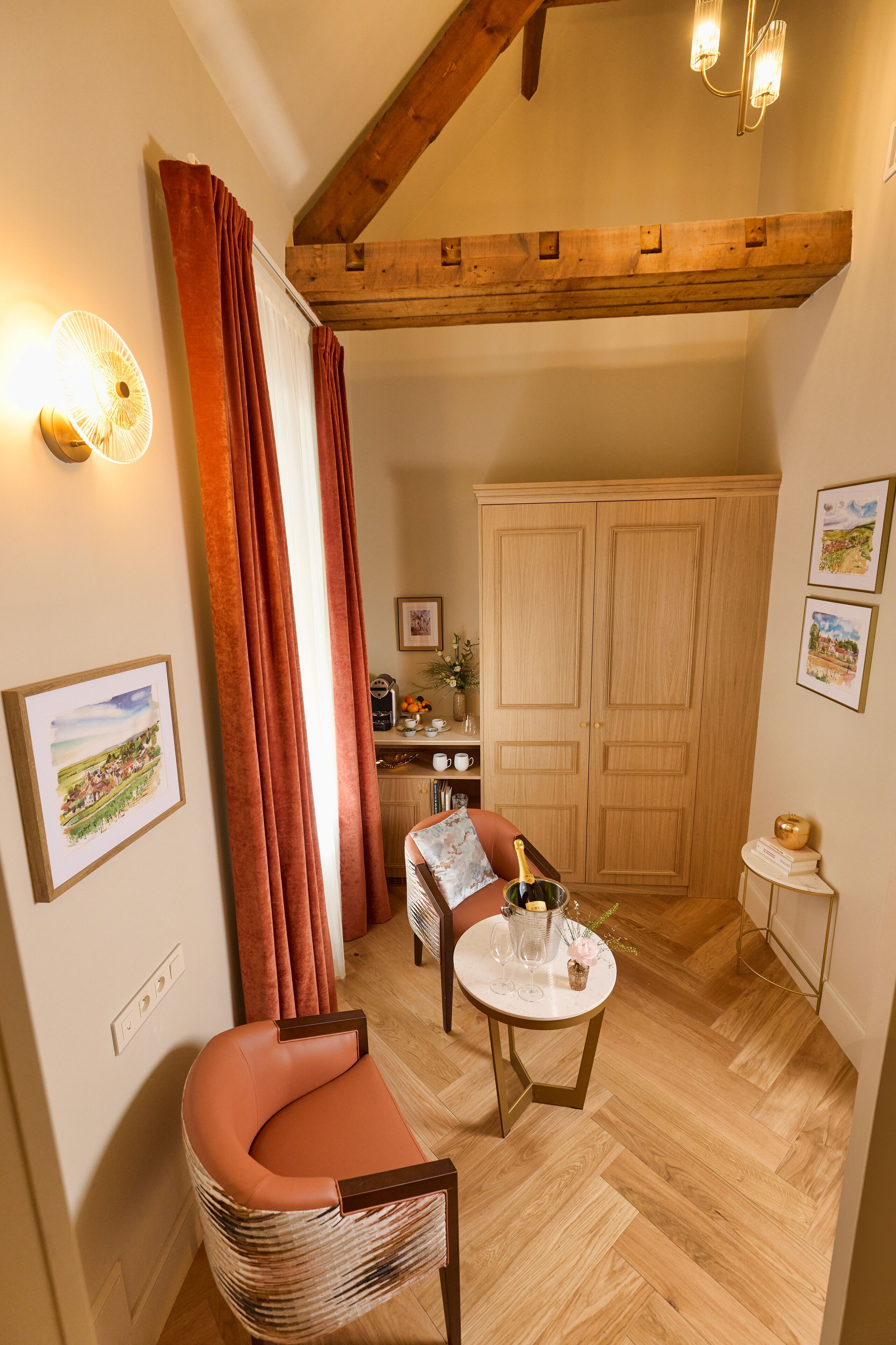 Una stanza accogliente con soffitto in legno, un divano, un tavolo con una bottiglia e dei bicchieri, e un armadio.