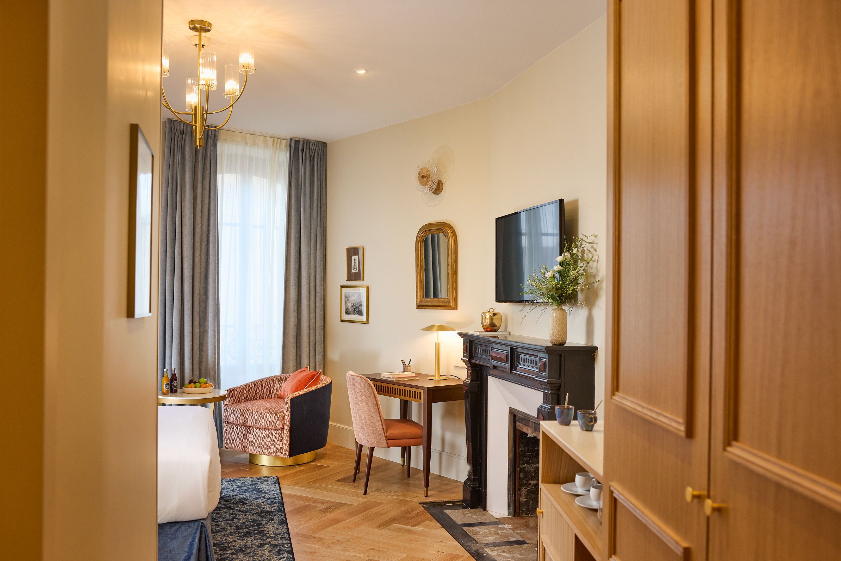Una habitación de hotel con comedor, chimenea, televisión y un espejo grande.