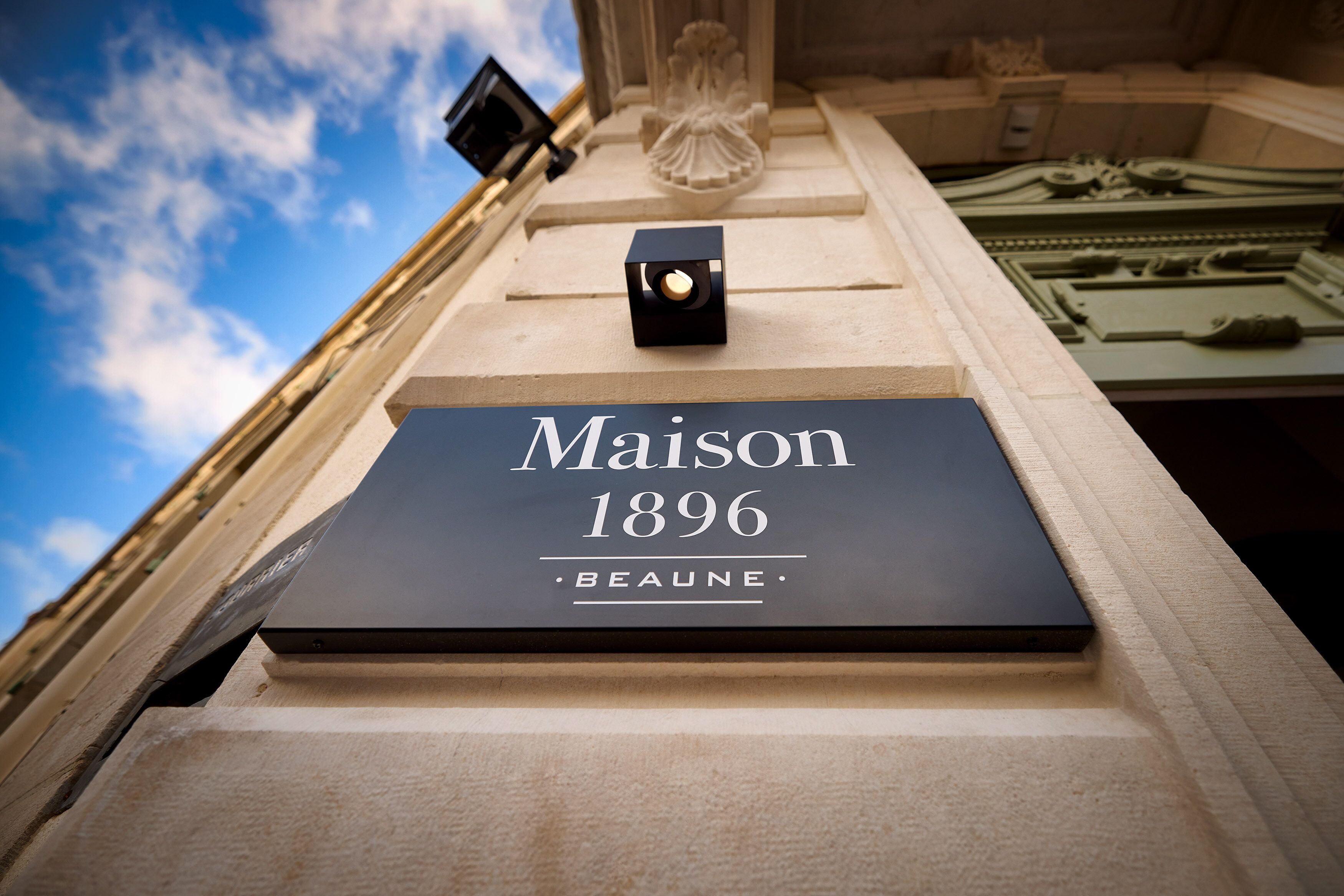 A sign with the text "Maison 1896 Beaune" on a building facade.