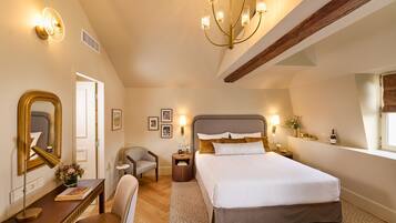 Quarto com uma cama grande, uma escrivaninha com cadeira, um espelho e um candelabro.