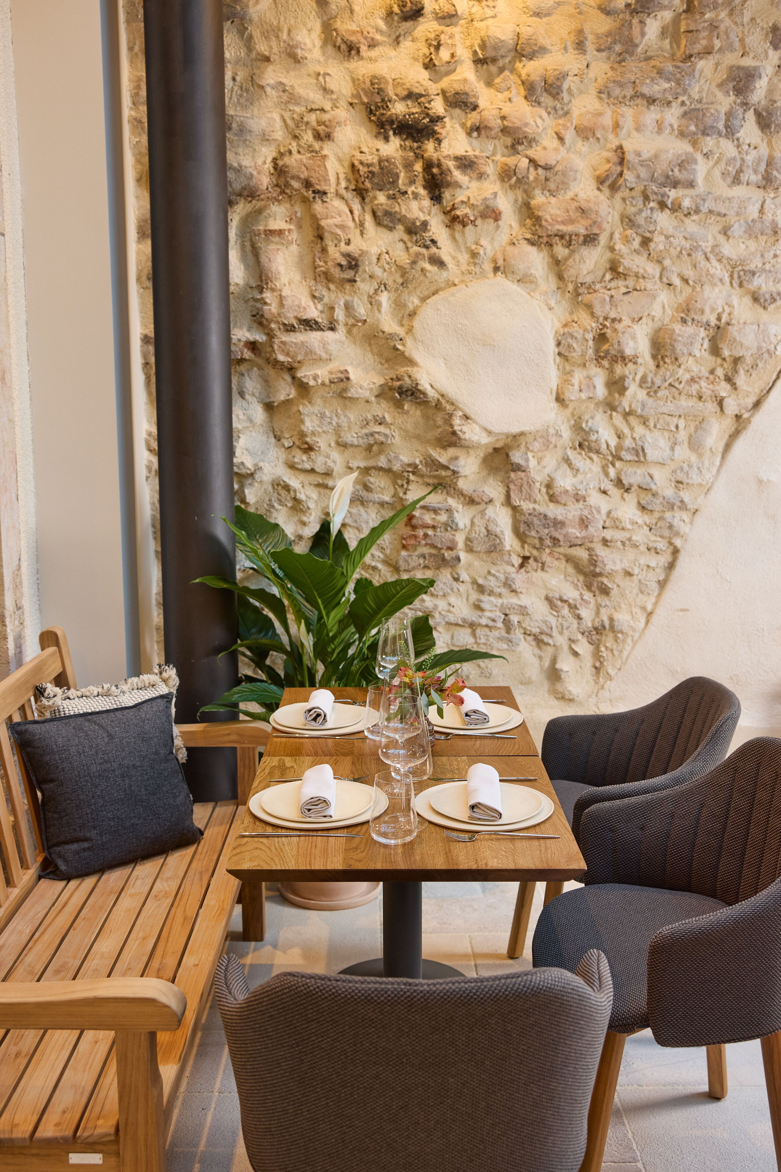 A cozy outdoor dining area with wooden furniture and a stone wall backdrop.