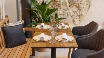 A cozy outdoor dining area with wooden furniture and a stone wall backdrop.